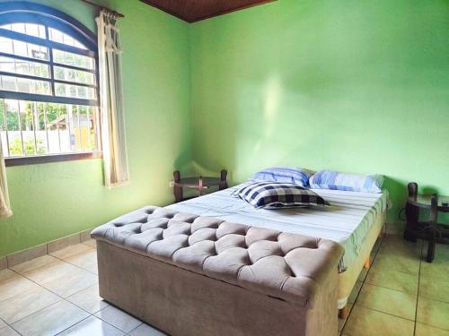a bedroom with a bed with green walls and a window at Casa 46 in São Sebastião