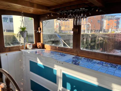 una cocina con azulejos azules en la encimera y ventanas en Judith Barge en Colchester