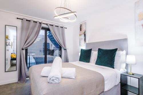 a white bedroom with a large bed with a window at Waterhouse Suite - Modern 2 Bed in Manchester City Centre- Perfect for Family, Business and Leisure Stays by Dreamluxe in Manchester