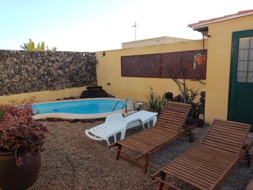 un patio con 2 sillas y una piscina en Villa Bruma Isabella, en Corralejo