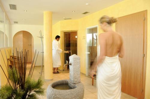 a woman in a white dress standing in a bathroom at Berghotel zum Zirm in Collalbo