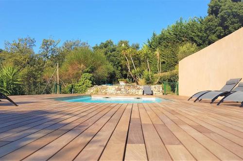 une terrasse en bois avec des chaises et une piscine dans l'établissement Superbe appartement dans villa provençale piscine et jardin, à Fréjus
