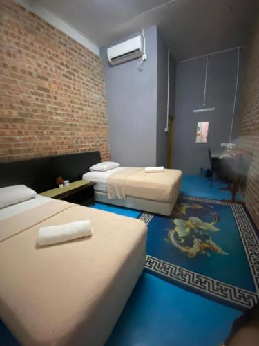 a room with two beds and a brick wall at Naja Hotel in Kampung Rahmat