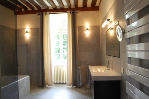 La salle de bains est pourvue d'un lavabo, d'une baignoire et d'une fenêtre. dans l'établissement Gîtes La Grande Ferme Crépon - à la campagne 5mn d'Arromanches et 10mn de Bayeux, à Crépon