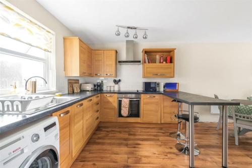 a kitchen with wooden cabinets and a black counter top at Bright flat in the heart of Chichester in Chichester