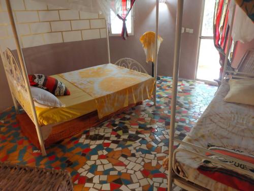 a room with two beds and a mosaic floor at Campement Baobab in Poponguine