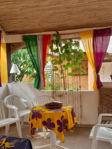 uma mesa e cadeiras num quarto com cortinas coloridas em Campement Baobab em Poponguine