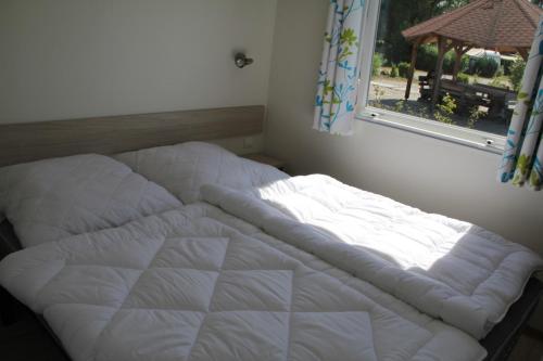 ein weißes Bett in einem Zimmer mit Fenster in der Unterkunft See-Campingpark Neubäuer See in Neubäu