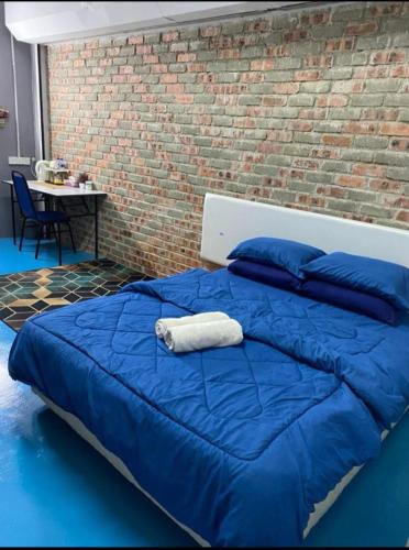a blue bed with blue pillows and a brick wall at Naja Hotel in Kampung Rahmat