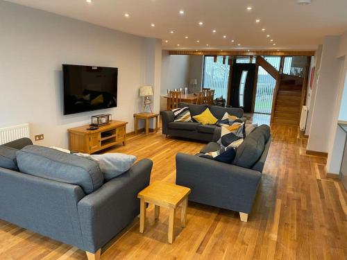 a living room with two couches and a flat screen tv at Dog friendly, Roof top hot tub, Panoramic views. in Torquay
