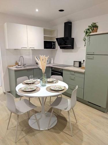 a kitchen with a white table with chairs and a refrigerator at Le COCON, appartement moderne et cosy in Dinsheim