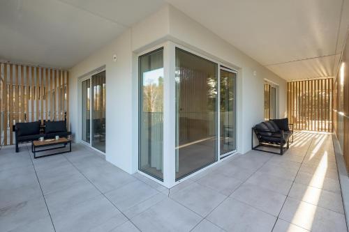 a room with glass doors and chairs on a building at Wyspa Uznam Promenada apartament na Wydmie in Świnoujście