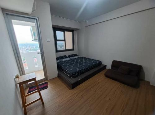 a bedroom with a bed and a chair and a window at Urbantown Serpong Age Room in Dukuh