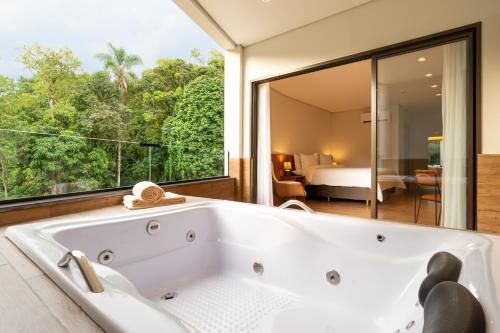 uma banheira na casa de banho com vista para um quarto em Vert Hotel Penedo em Penedo
