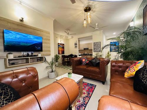 a living room with leather furniture and a flat screen tv at Panaromic Perch With Swimming Pool in Lucknow