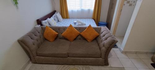 um sofá com quatro almofadas numa sala de estar em Luca Homes Studio Apartment em Mombaça