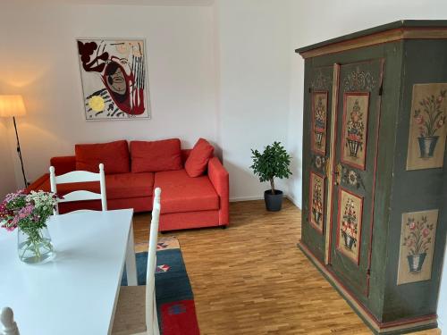 ein Wohnzimmer mit einem roten Sofa und einem Tisch in der Unterkunft Ruhige Ferienwohnung in Oberhaching bei München in Oberhaching