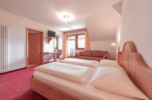 a hotel room with two beds and a couch at Berghotel zum Zirm in Collalbo