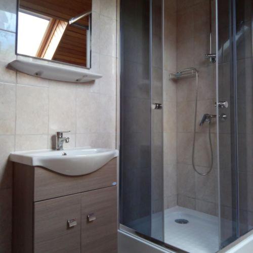 a bathroom with a sink and a shower with a glass door at Strandi Apartmanok- Boglárka in Balatonmáriafürdő