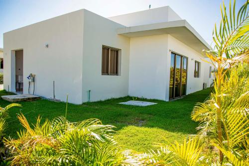 a white house with a green yard at Beautiful Village 3 bedrooms Furnished Pool residencial Velero punta cana in Punta Cana