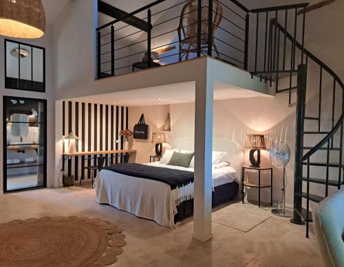 a bedroom with a bed with a spiral staircase at Hôtel Le Cottage de Sophie in Valernes