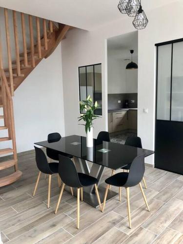 une salle à manger avec une table et des chaises noires dans l'établissement Grange 5 minutes du centre-ville et gare avc wifi, à Auxerre