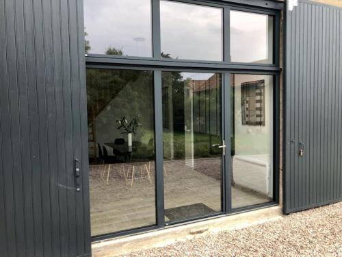 une extension vers une maison avec portes coulissantes en verre dans l'établissement Grange 5 minutes du centre-ville et gare avc wifi, à Auxerre