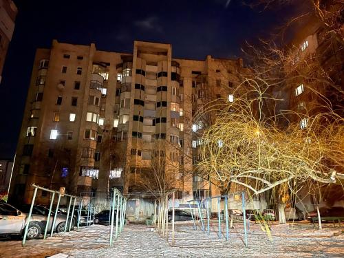 een hoog gebouw 's nachts met bomen ervoor bij Brand new apartment Chisinau not far from the airport in Chişinău