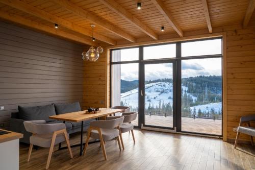 a dining room with a table and chairs and a large window at Шале Green Land in Bukovel