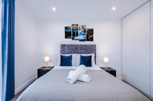 um quarto com uma grande cama branca com almofadas azuis em Sterling Suite - Modern 2 Bedroom Apartment in Birmingham City Centre - Perfect for Family, Business and Leisure Stays by Dreamluxe em Birmingham