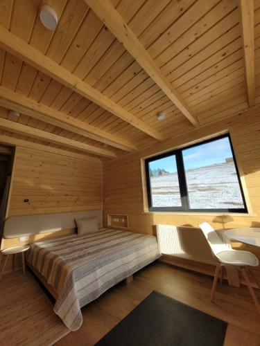 a bedroom with a bed and a desk and a large window at Шале Green Land in Bukovel