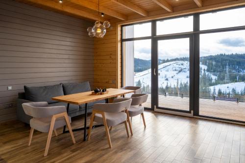 a dining room with a table and chairs and a large window at Шале Green Land in Bukovel