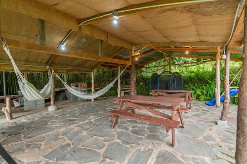 a patio with two picnic tables and hammocks at Cabaña El Manzano: Vistas increíbles y Mirador in Turrialba