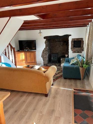 a living room with a couch and a fireplace at Traditional Stone cottage in heart of the village in Llangwm