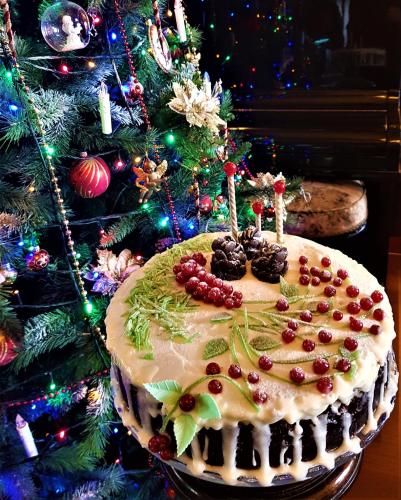 a christmas cake on a table next to a christmas tree at Conacul Malul Alb in Râmnicu Vâlcea