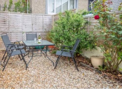 a patio with a table and two chairs in front of a fence at Traditional Stone cottage in heart of the village in Llangwm