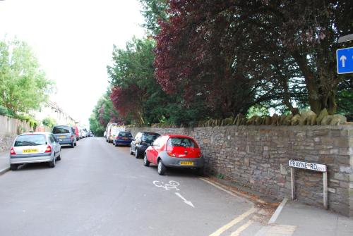 a street with cars parked next to a brick wall at Clift Guest House in Bristol