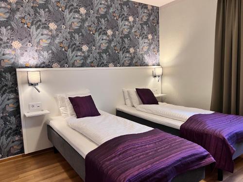 two beds in a room with purple and white at Hotel Wictoria in Mariestad