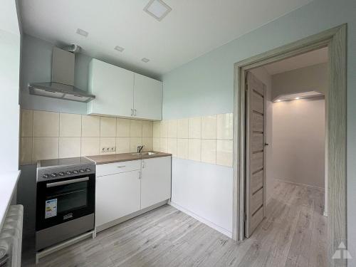 a kitchen with white cabinets and a stove top oven at Ziemeļblāzma in Rīga
