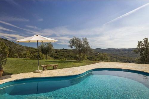 una piscina con sombrilla y banco en Villa Bolara by Briskva, en Grožnjan