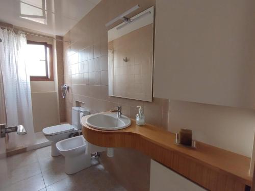 een badkamer met een wastafel, een toilet en een spiegel bij Apartament Tere in Oliva