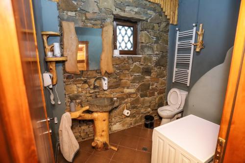 a stone walled bathroom with a sink and a toilet at Shtepia Tradites Gjinar in Elbasan