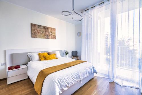 a white bedroom with a bed and a large window at [5 min walk from subway] Elegant & Modern in Milan