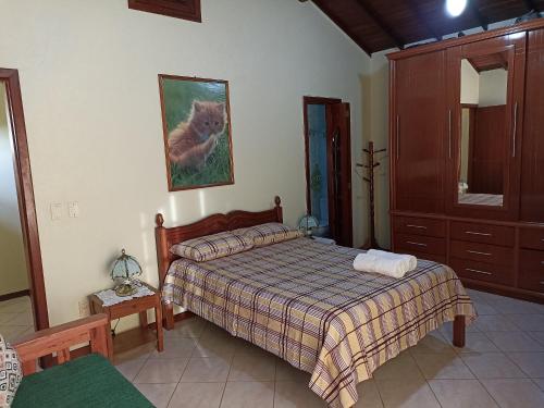 a bedroom with a bed and a cat picture on the wall at Casa Azul em Búzios in Búzios