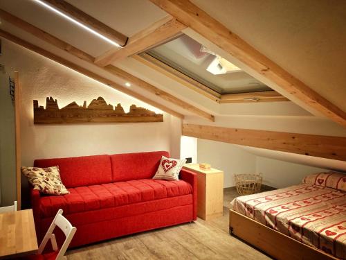 a living room with a red couch and a bed at Ad Alba di Canazei una finestra sulla Marmolada in Alba di Canazei