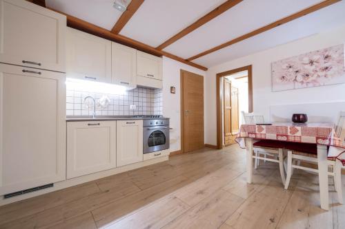 a kitchen with white cabinets and a table and a dining room at Cesa alla Cascata in Canazei