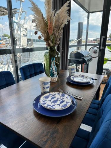 une table en bois avec des assiettes bleues et un vase avec des fleurs dans l'établissement Premium Hausboot Trave Traum, à Lübeck