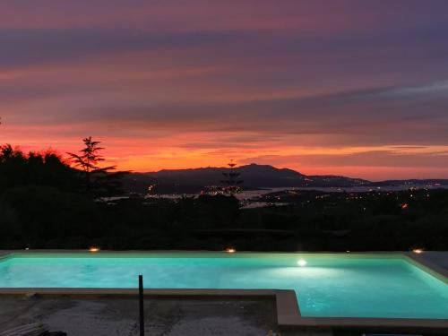 a swimming pool with a sunset in the background at Casa Mariposa Porto Rotondo in Rudalza