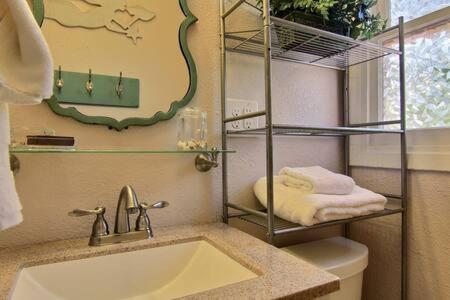 Un baño con lavabo, inodoro y espejo. en Spanish Village Cottage w private cabana, en Port Aransas