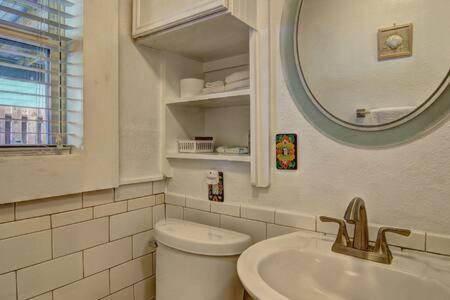 Un baño con inodoro, lavabo y espejo. en Spanish Village Sunshine Cottage, en Port Aransas